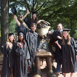 Students in mortarboard caps surround the Cocky statue on Davis Field